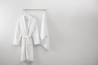 Hanger,With,Clean,Bathrobe,And,Towel,On,Light,Wall.,Space