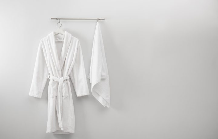 Hanger,With,Clean,Bathrobe,And,Towel,On,Light,Wall.,Space